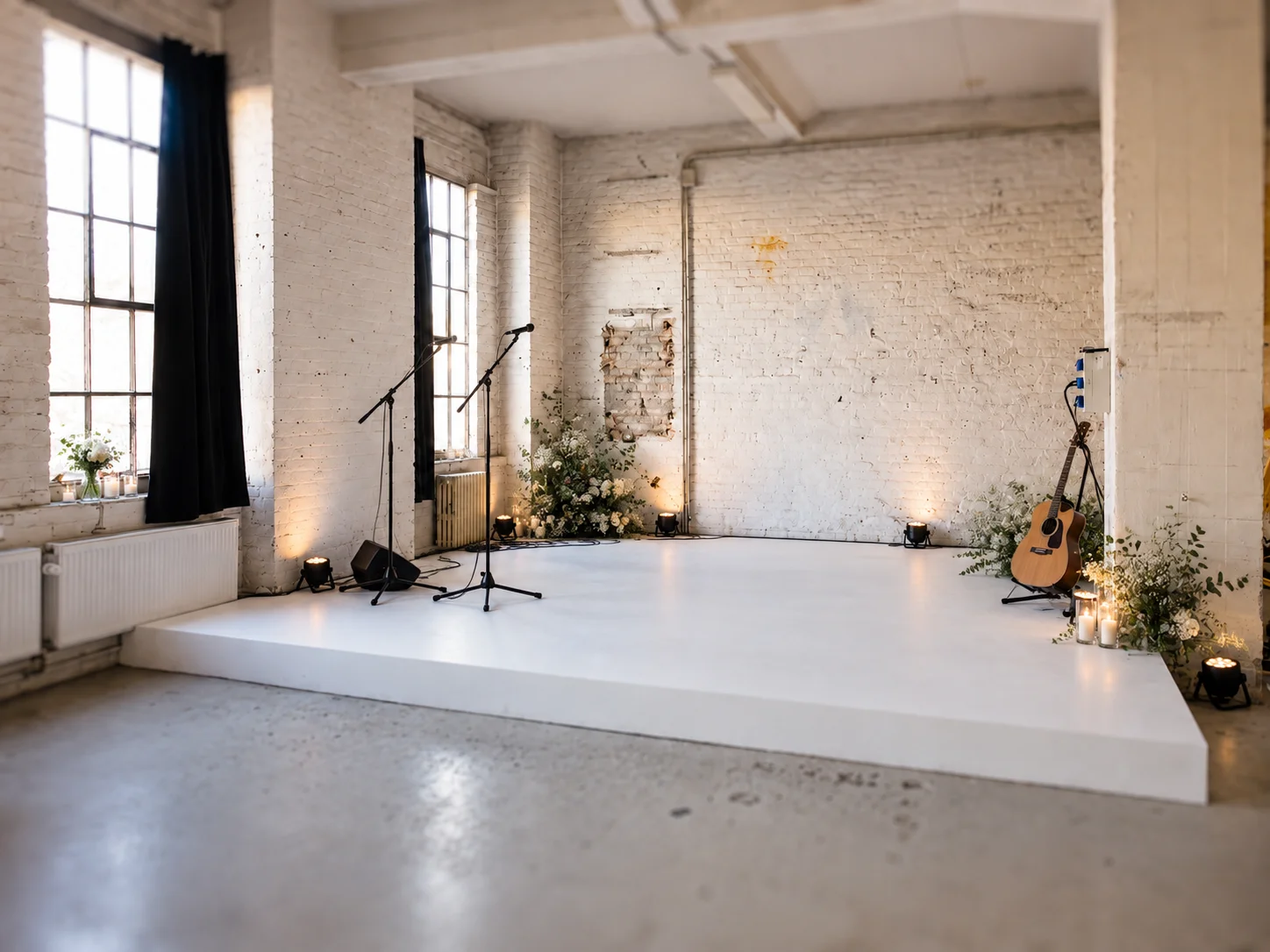 Modern loft with stage with white platform, microphones, guitar and industrial design in Berlin.